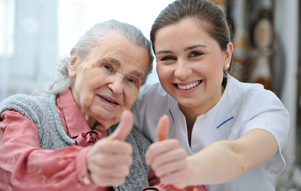 nurse and elderly patient posing with their thumbs up for a picture