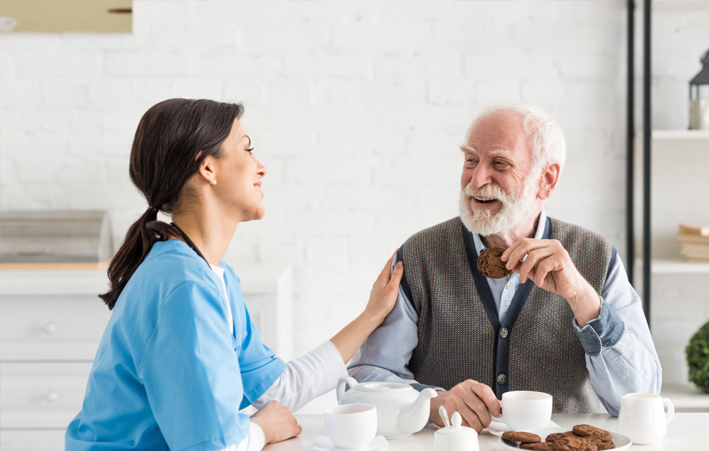 nurse having coffee and cookies with elderly patient